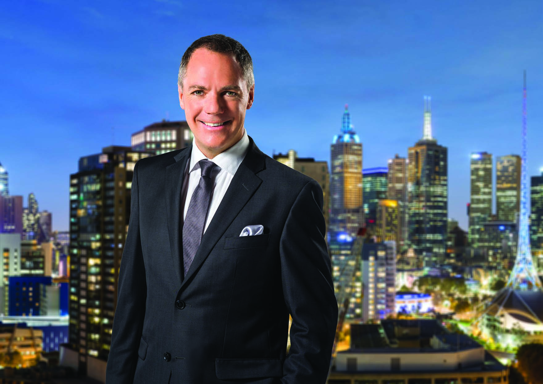 Scott Banks in a suit with Melbourne’s skyline behind him
